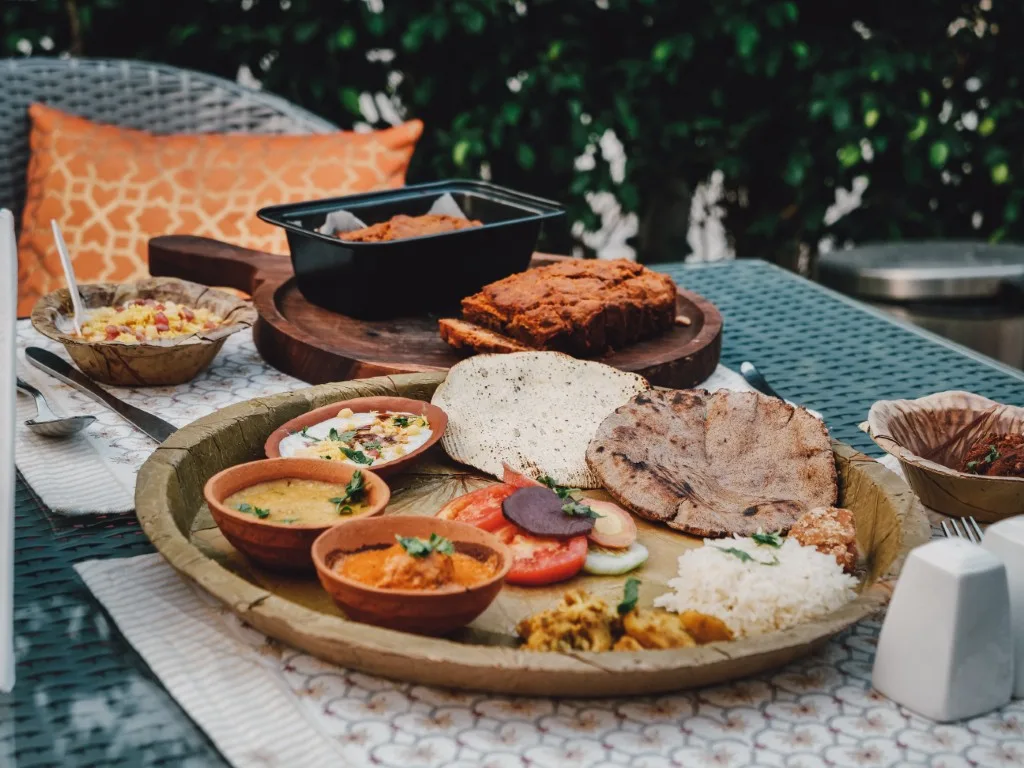 A Pattal Ki Dawat thali on a leaf plate, with dal, curries, rotis and rice in clay bowls