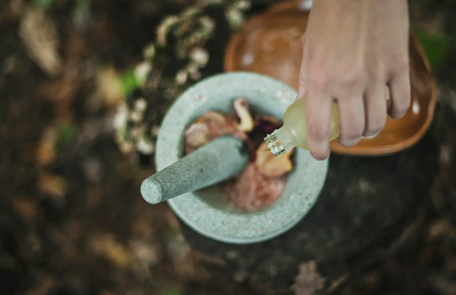 Ayurvedic herbs and oil being prepared by hand with a mortar and pestle