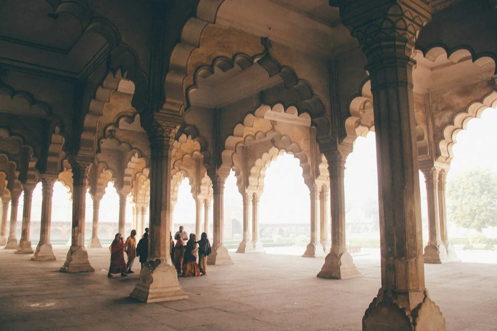 Travellers walk through the arched stone colonnades of the Red Fort in Delhi