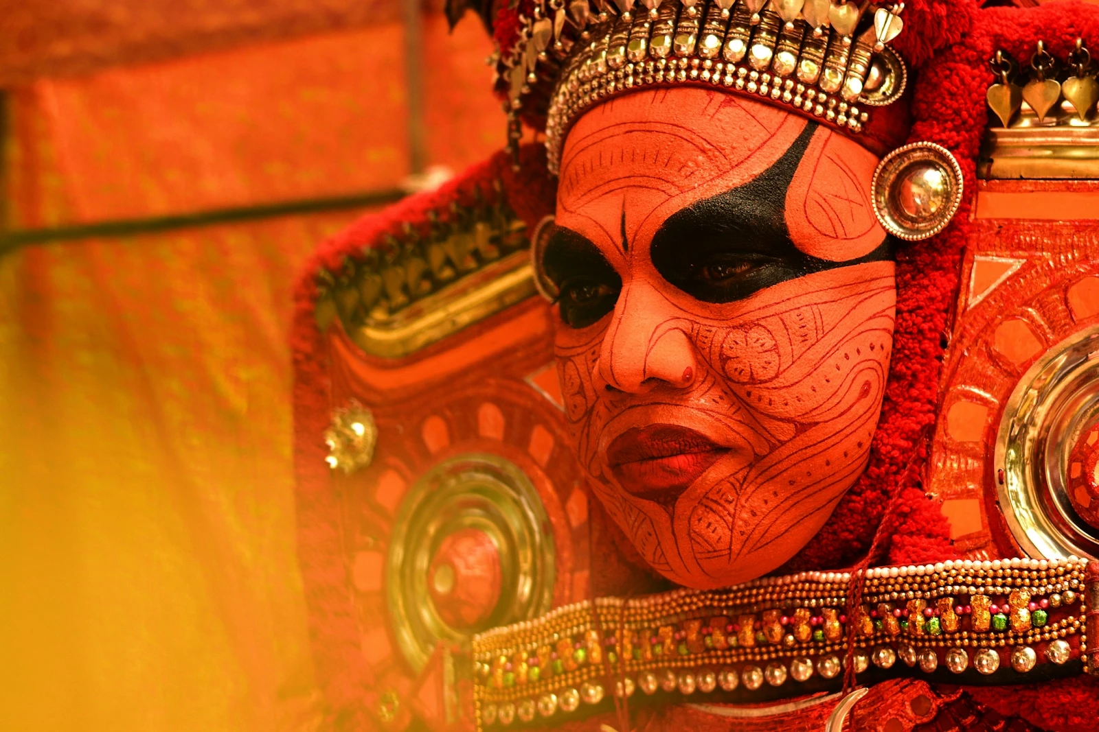 A Theyyam performer in northern Kerala in elaborate red face paint and costume during a night-time ritual