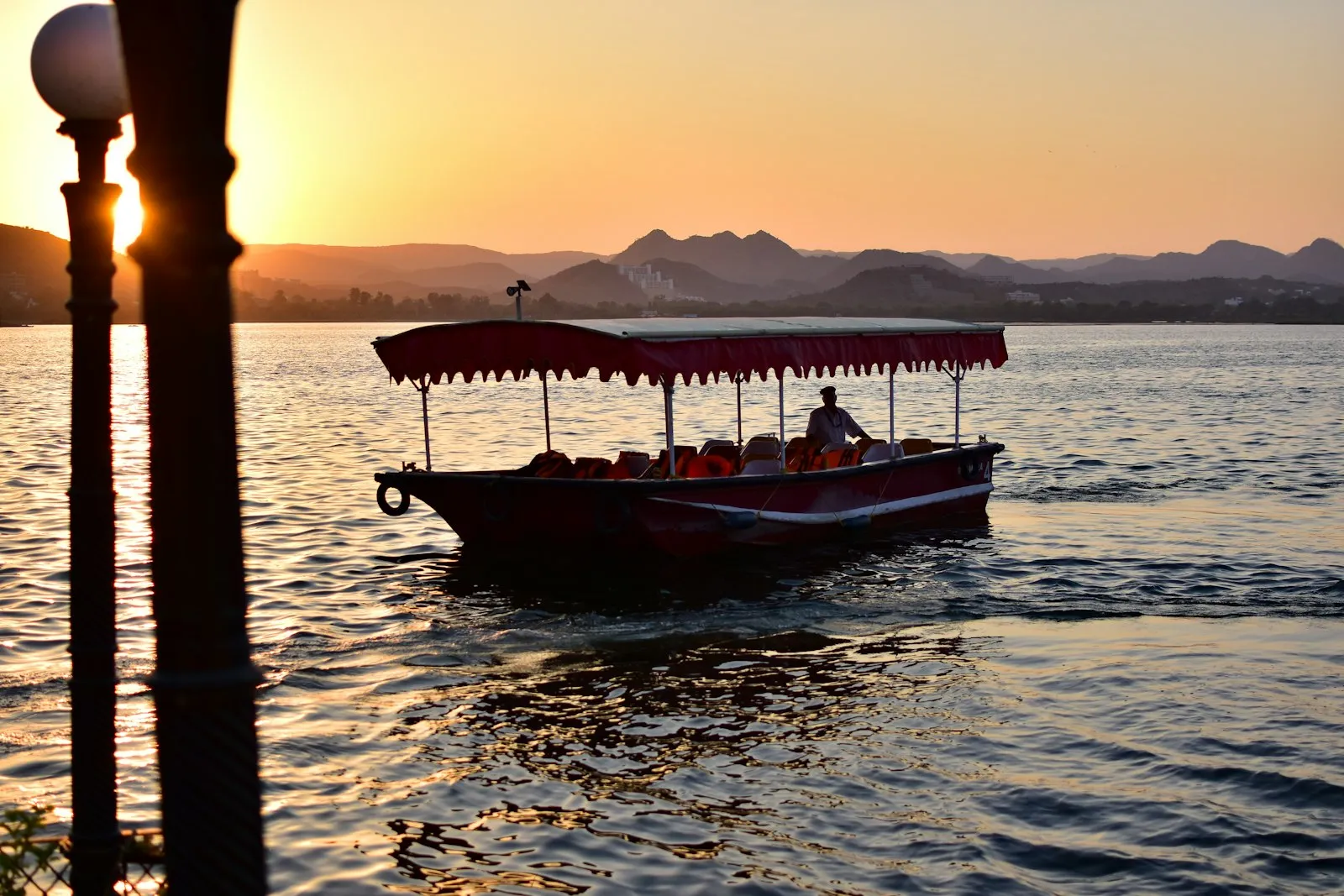 A boatman rows a small boat across Lake Pichola in Udaipur in soft afternoon light