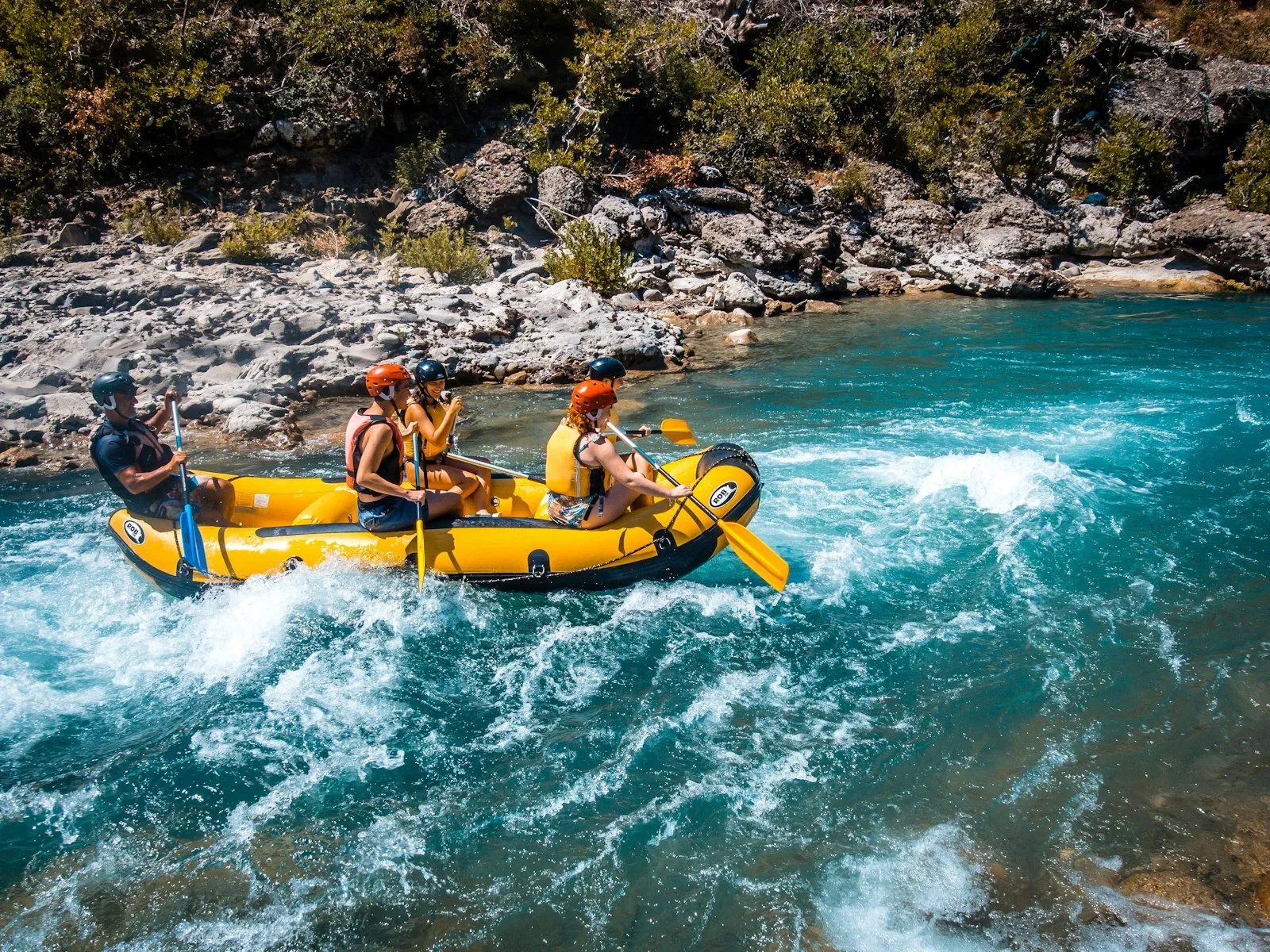 A crew of paddlers riding a raft down a fast-flowing river through white water
