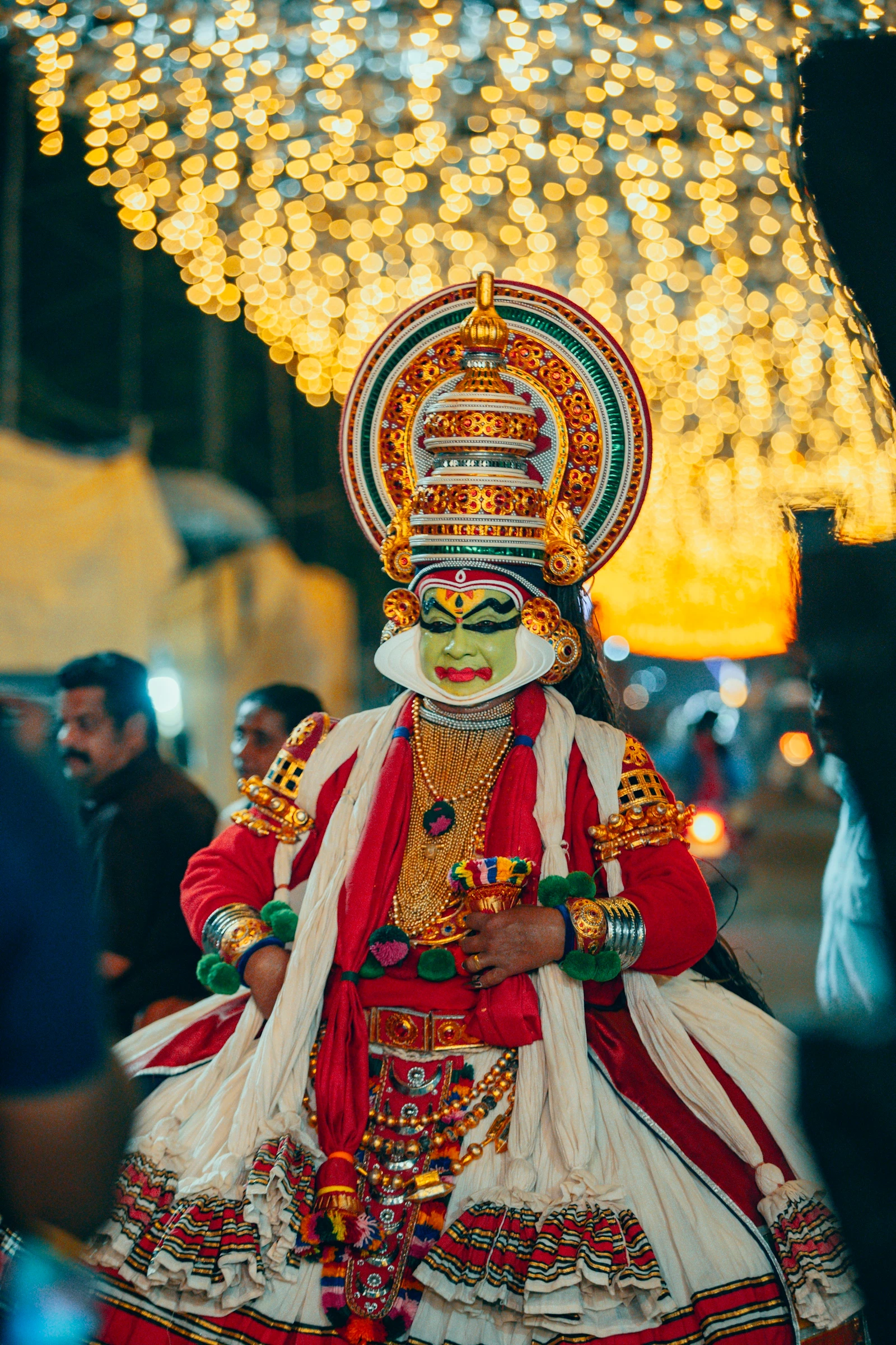 A Kathakali dancer in traditional green face paint and a towering headdress performing in Kerala