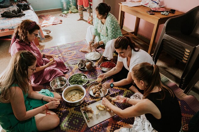 Travellers preparing vegetables together on the floor with their host during an Indian home cooking class