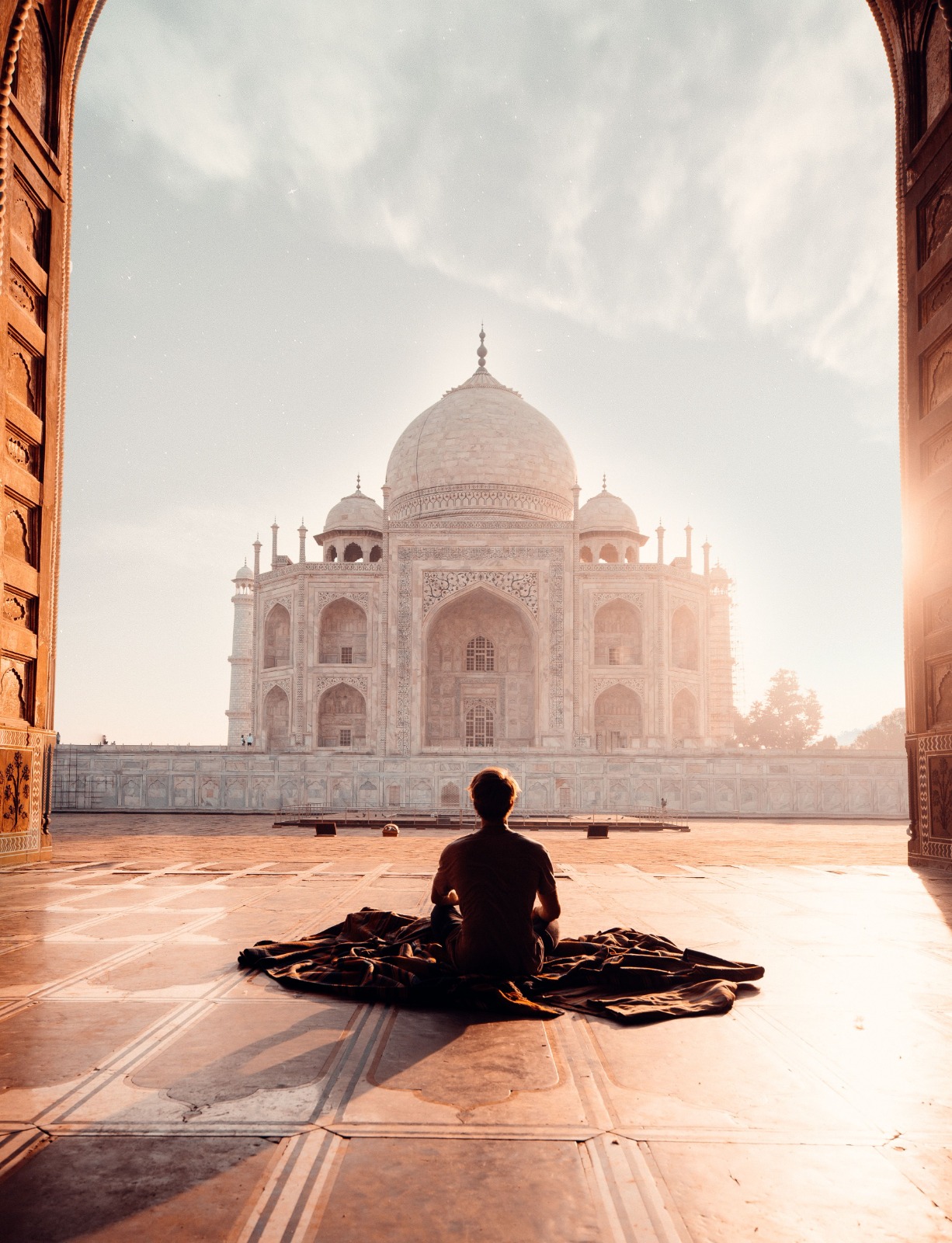 Person sitting in meditation facing the Taj Mahal at sunrise